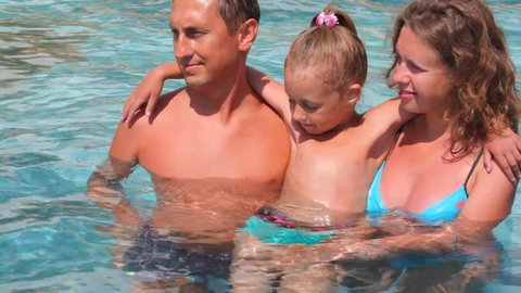 happy family with girl has fun together in swimming pool 