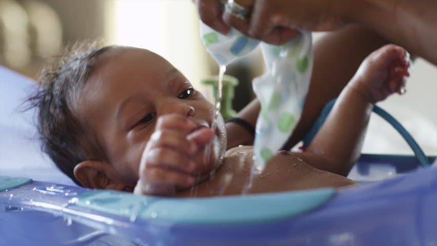 Close Up Woman washing baby boy (2-5 months) in bathtub 