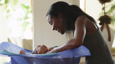 Medium Shot Woman washing baby boy (2-5 months) in bathtub 