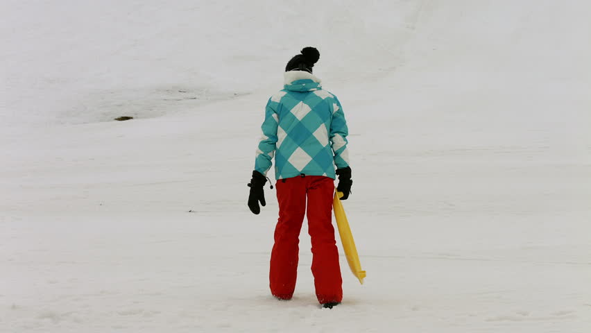 Young girls playing in the snow with sledges climbing a hill 4K