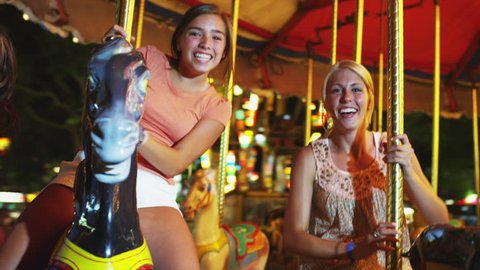 Medium Shot POV Girls (16-17) riding carousel in amusement park 