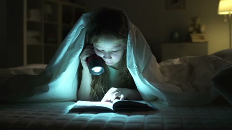 Dolly of girl resting in bed and reading aloud with the help of lantern