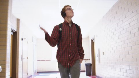 SLO MO Medium Shot Male student wearing headphone dancing in school corridor 
