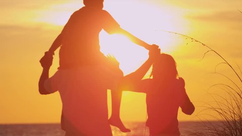 Ethnic Family Vacation Sunset Beach - Young boy on fathers shoulders as family in silhouette stand on beach watching sunset slow motion shot on RED EPIC