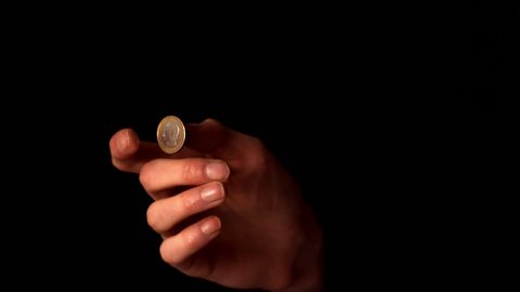 Woman tossing a euro coin on black background in slow motion