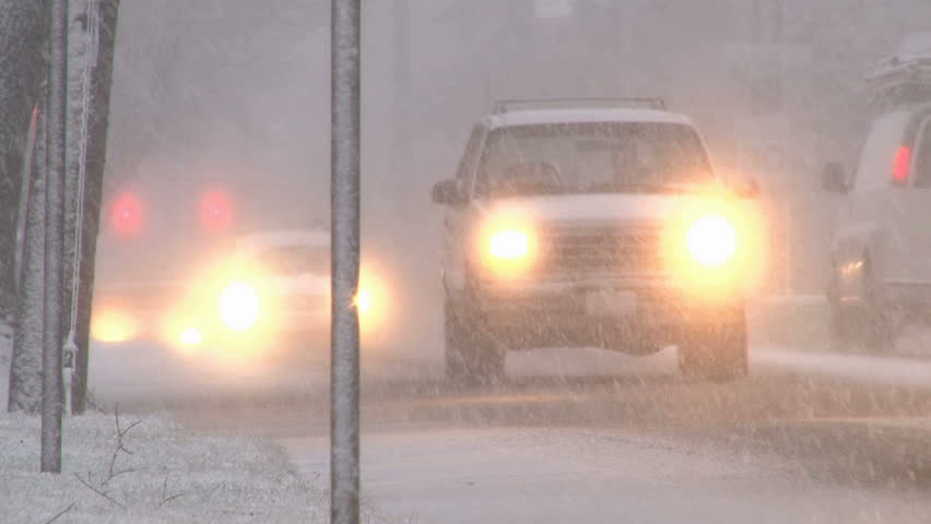 Blizzard conditions with vehicles driving on snow filled roads in Portland,