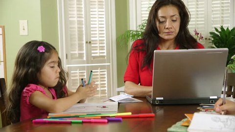A single mom worries about how to pay bills while children color peacefully unaware of the stress she is feeling.
