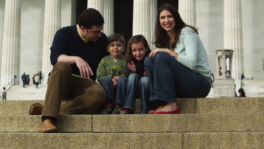Medium Shot Portrait of family with two children (4-5, 6-7) sitting on steps in front of Abraham Lincoln Memorial , Washington D.C, USA