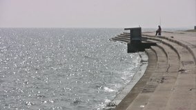 Video of a fisherman on the sea wall steps of Corpus Christi Texas. Ocean bay fishing from local park.