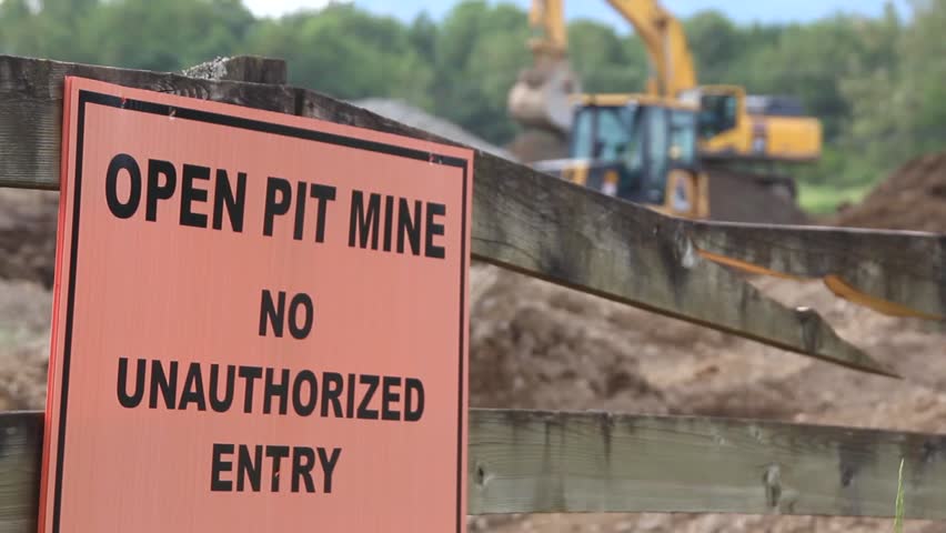 Open Pit mine and a warning to stay away/Open Pit Sign/Open Pit signage and activity in the background. 