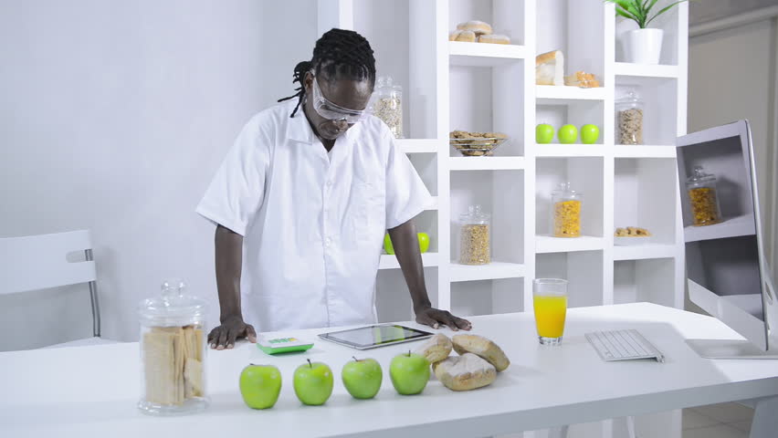 African American lab technician studying nutrition of food with a tablet computer 
