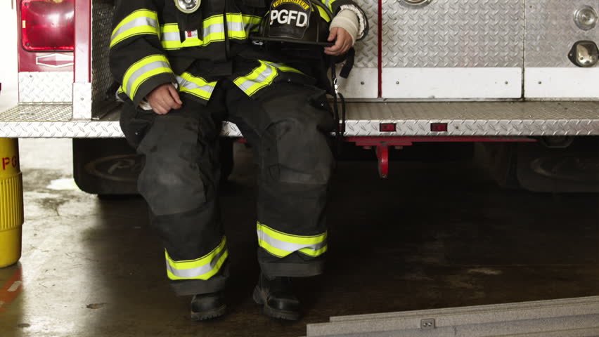 Medium Shot Portrait of female firefighters sitting at back of fire engine in garage