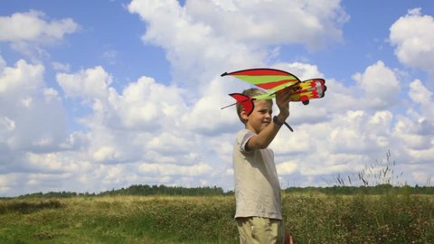 boy flying toy airplane in the field 