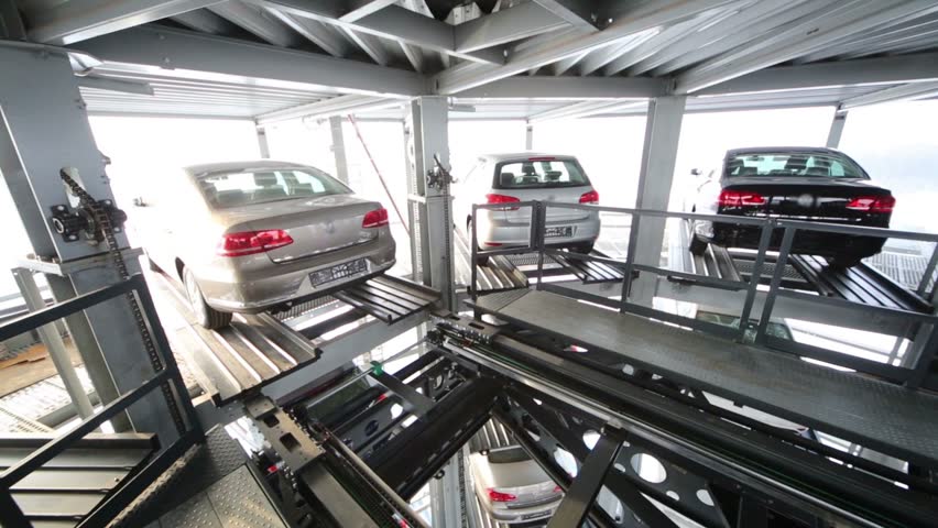 Car moves to empty elevator in modern glassy tower for car parking