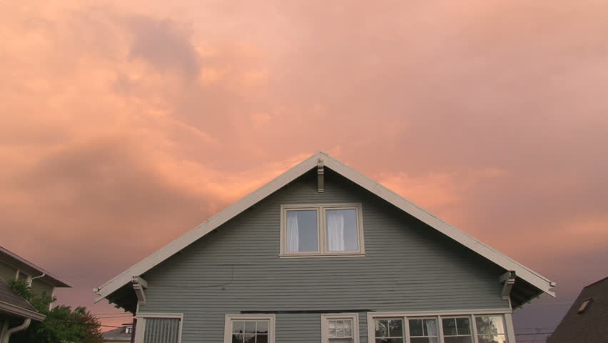 Beautiful clouds move over house during sunset.