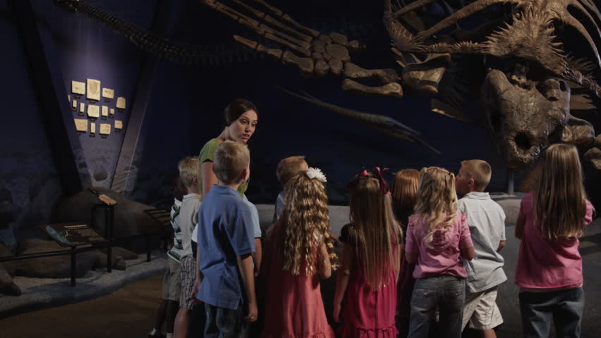 Medium Shot Young woman with group of children (4-5, 6-7, 8-9) in natural history museum