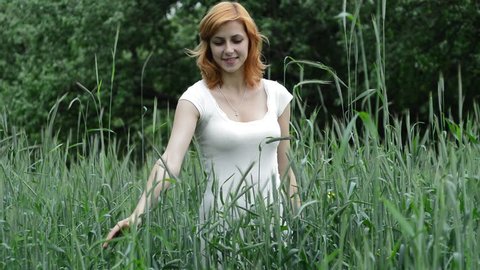 girl stroking hands ears of wheat in field