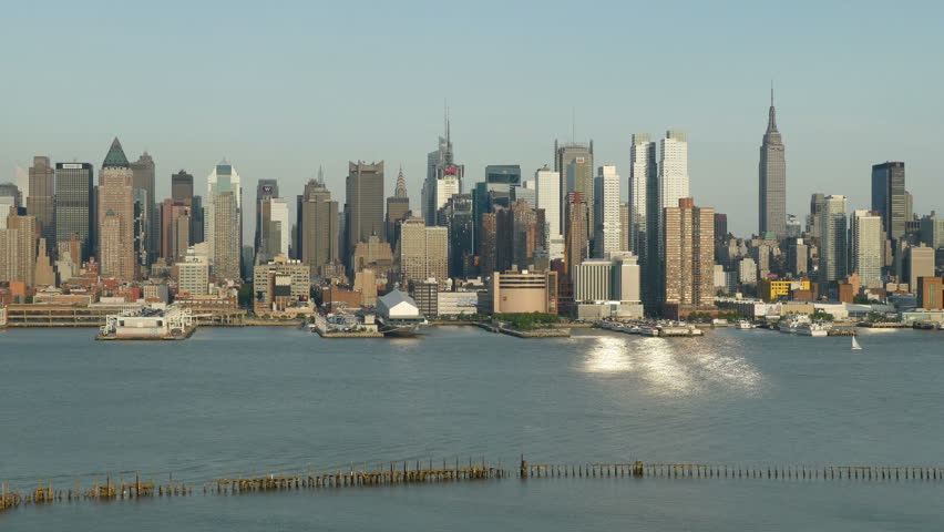 Sunlight reflects off the windows of the mid-town Manhattan skyline and the Hudson River during late afternoon.