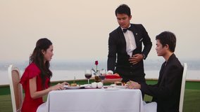 Asian people eating in hotel restaurant, man, woman, couple, young man working as waiter serving bread to customers celebrating anniversary on resort terrace. Leisure, lifestyle, fun, romance. 2of7 - Powered by Shutterstock - Get 15% off with code: PIKWIZARD15