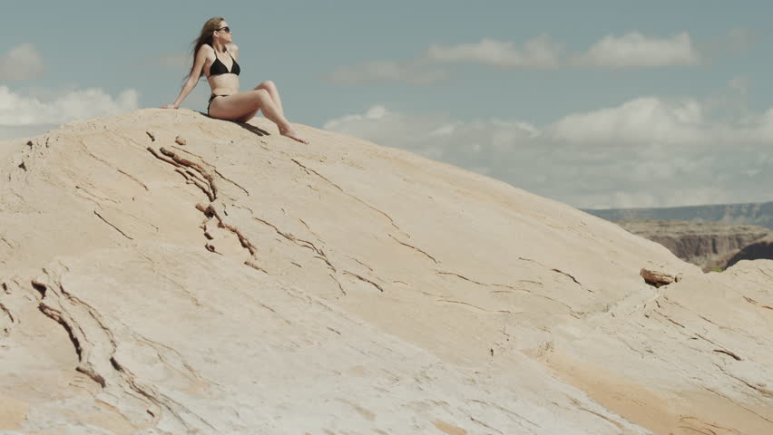 Wide Shot Young woman relaxing on rock near Lake Powell / Utah, USA