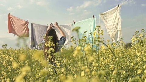 Ecology Living Concept Pretty Girl Hanging Clothes on Summer Field