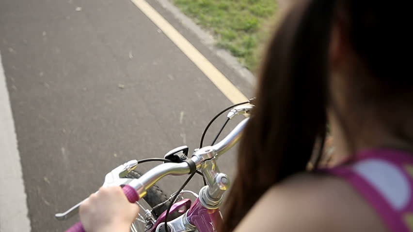 Little girl cycling in park on a pink bike. Slow motion
