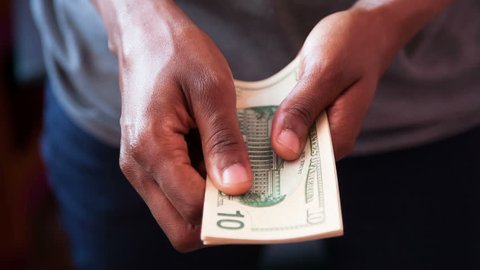 Close up of a african american person counting 10 dollars bills 
