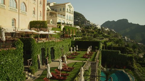 Wide Shot Pan People walking down stairs by mansion on cliff / Ravello, Campania, Italy