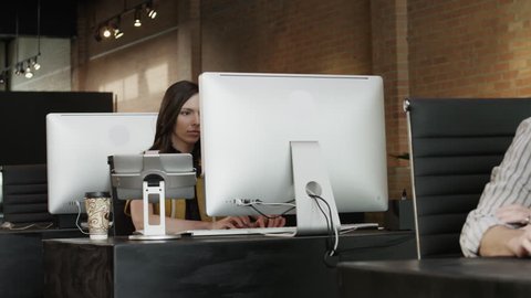 Medium Shot Female office worker using computer and drinking coffee in office
