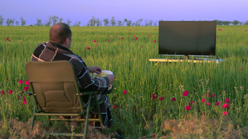 Man watching television in the green field