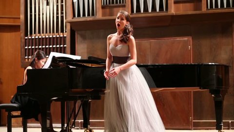 Woman pianist plays the piano and beautiful singer emotionally sing opera song