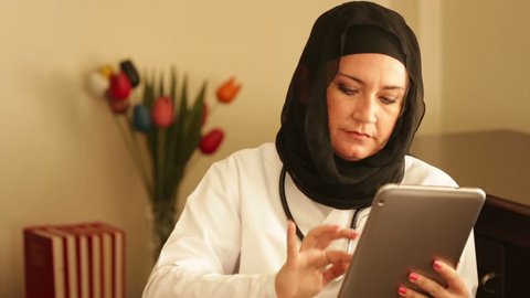 Female muslim doctor working with digital tablet in office