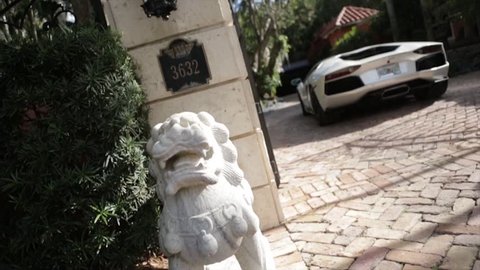 Cinematic Lamborghini driving through mansion gates slider shot