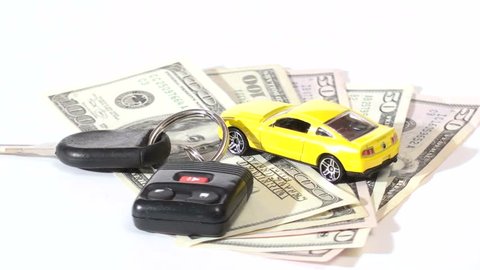 Seamless loop of car key and model car on stack of hundred dollar bills isolated on white V4
