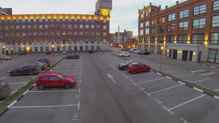 Car parking in courtyard among red brick buildings at evening. Aerial view