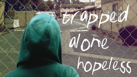 A young man deals with depression on his own, fenced in. The words "trapped", "alone" and "hopeless" are tracked next to him.