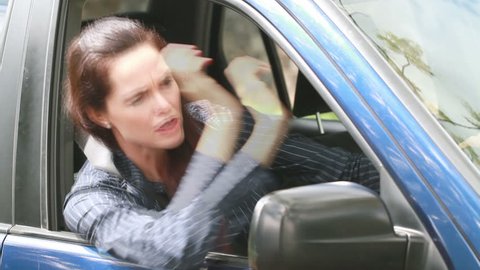 A frustrated furious woman is angry and screams in her car. 