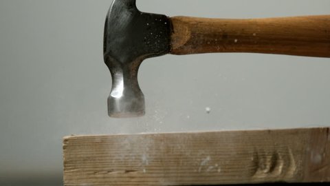 Hammer hitting a nail into wooden plank in slow motion