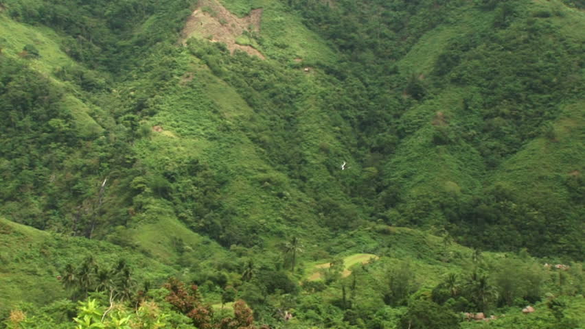 Wide shot of helicopter flying through mountains