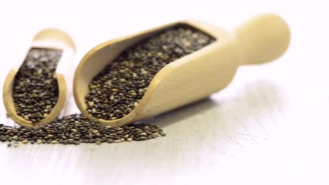 Chia seeds in wooden scoops on wooden table.