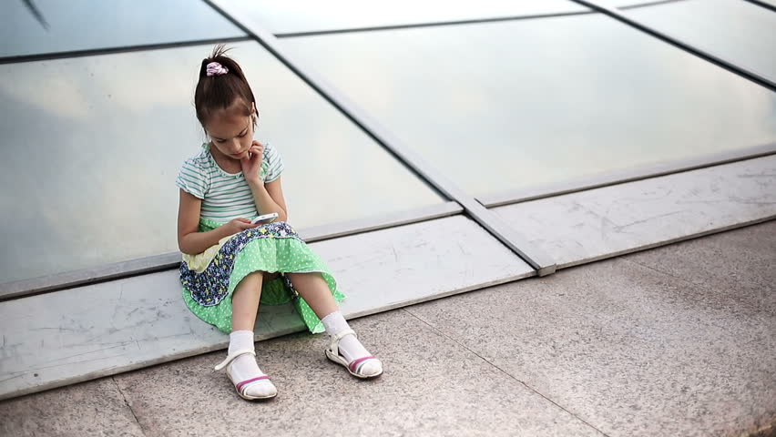 Beautiful child little girl kid enjoys smartphone. Model Elizabeth Andreeva