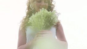 Beauty girl with bunch of wild flowers outdoor. Happy young woman on spring or summer field. Allergy free concept. Girl smelling flowers. Slow motion video footage 1080 full hd. High speed camera shot