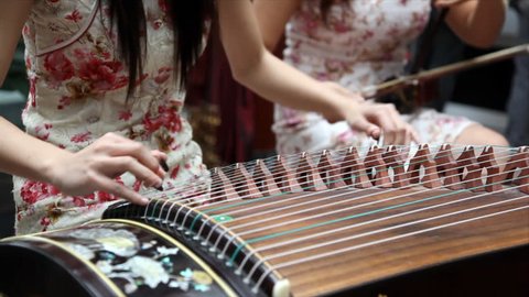 Chinese traditional musician playing Chinese guzheng. Guzheng, also called zheng or Chinese plucked zither,is a plucked half-tube zither with movable bridges and strings