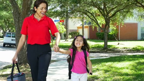 A cheerful single mom playfully twirls her little girl around as she walks her home from school. Slow motion footage. 