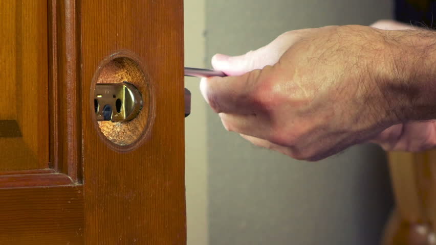 A handyman removing a door knob from a front door.