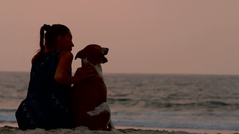 woman hugs her dog at sunset