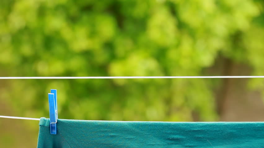 Green clothes hanging to dry on a laundry line outdoor. Housework.