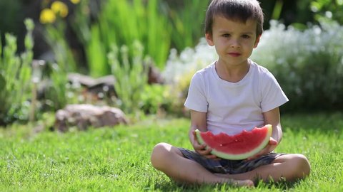 Boy, eating watermelon in the garden, summertime