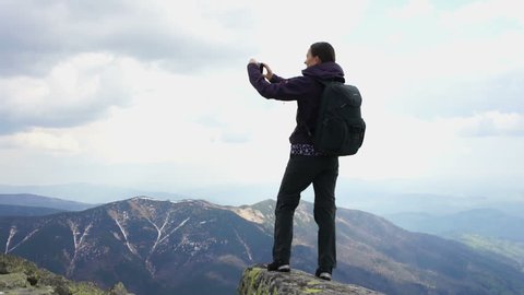 Young woman uses a smart phone to video a beautiful view in the mountains