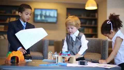 Two boys play with toy train and girl play with stationery in business center